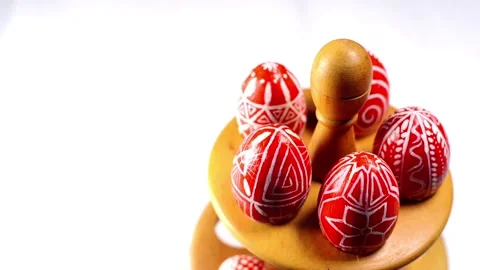 Red easter eggs with folk pattern lay and revolve on wooden stand for eggs Stock Footage 127886666