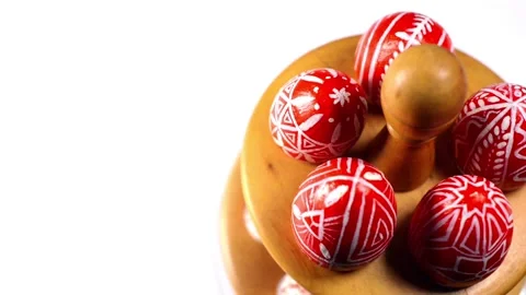 Red easter eggs with folk pattern lay and revolve on wooden stand for eggs Video stock 127886727
