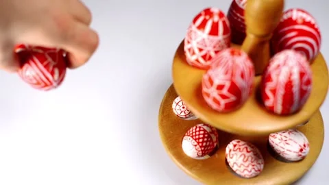 Red easter eggs with folk pattern lay on wooden stand for eggs. Man rotate egg Stock Footage 127886780