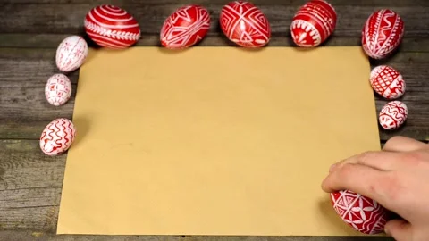 Red easter eggs with folk pattern lay on edge of sheet of paper. Manrotate egg Video stock 127887083