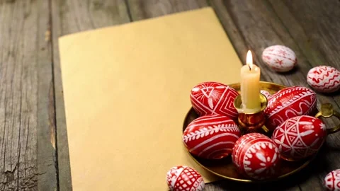 Red easter eggs with folk pattern lay on candlestick. Man rotate egg Stock-Footage 127887204