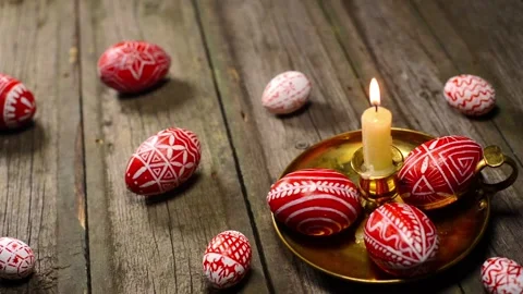 Red easter eggs with folk pattern and on candlestick. Man rotate one egg Stock Footage 127887326