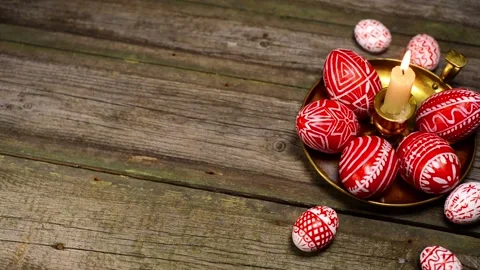 Red easter eggs with folk pattern lay on brass candlestick. Man rotate egg Stock Footage 127887464