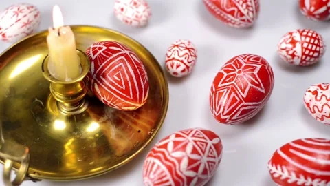 Red easter eggs with folk pattern lay around and on candlestick. Top view Stock-Footage 127888488