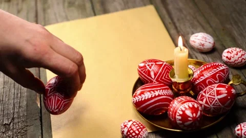 Red easter eggs with folk Ukrainian pattern lay on candlestick. Man rotate egg Video stock 127887240