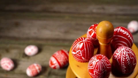 Red easter eggs with folk white pattern lay and revolve on wooden stand for eggs Stock-Footage 127887585