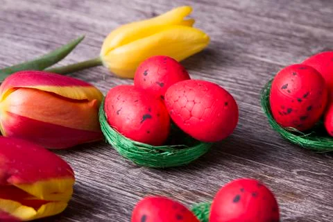 Red Easter eggs on green nest and colorful tulips Stock Photos