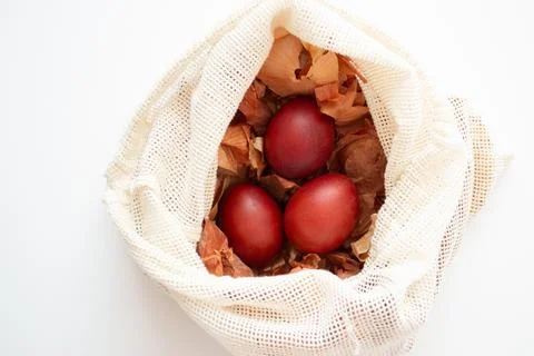 Red Easter eggs in onion husks lying in a sack top view. Stock Photos