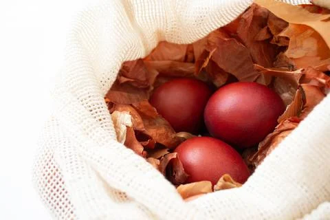 Red Easter eggs in onion husks lying in a sack top view. Stock Photos