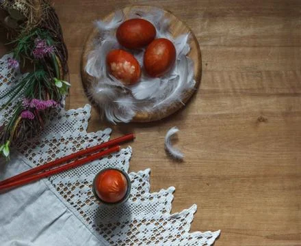 Red Easter eggs in white feathers on wooden background Stock Photos