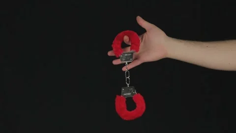 Red-edged handcuffs on a black background Stock Footage 186082925