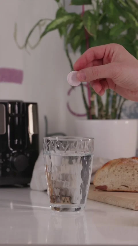 Red effervescent pill falling into water and starting to fizz Stock Footage 332724600