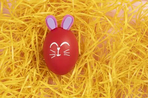 Red egg with easter rabbit drawn on yellow straw background Foto stock