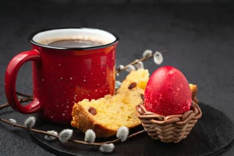 Red Egg in a wicker stand, Easter cake and cup of coffee on black slate dish  Stock Photos