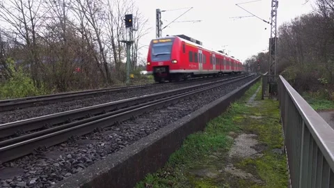 Red electric commuter train passing by on a cloudy day Stock Footage 306933396