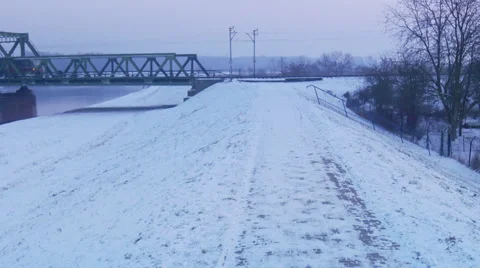 Red Electric Train is Driven by Old Railroad Bridge Through a River Zoom In Stock Footage 59798245