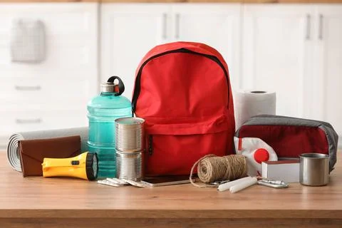 Red emergency backpack with necessities on table in kitchen Stock Photos
