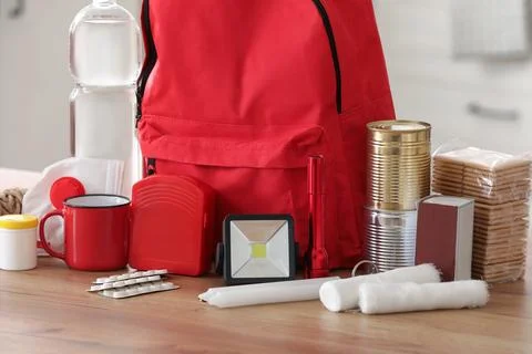 Red emergency backpack with necessities on table in kitchen, closeup Stock Photos