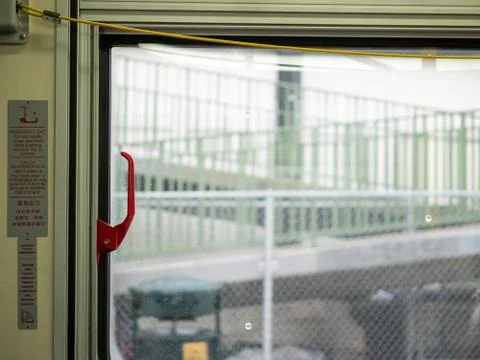 Red emergency exit handle on window on moving public transportation bus Stock Photos
