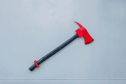 Red emergency fire axe mounted on a gray ship bulkhead wall Фото