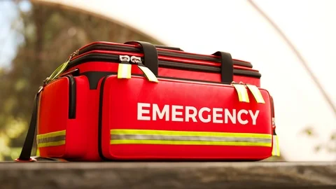 The red emergency first aid bag on a wooden table outdoors. Garden environment. Stock Footage 112599482