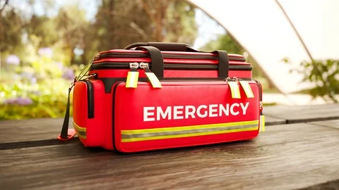 The red emergency first aid bag on a wooden table outdoors. Garden environment. Stock Footage 112599882