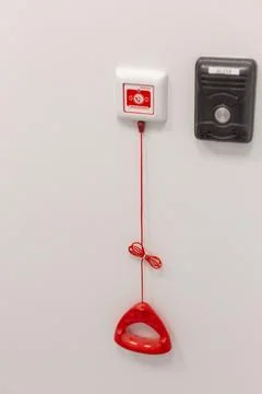 A red emergency pull cord system on a white wall in a clinical setting. Stock Photos