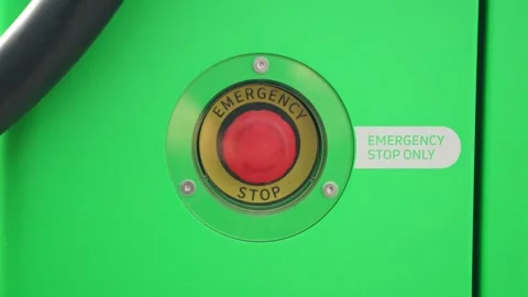 Red Emergency Stop Button Mounted on Green Equipment Stock Footage 335290631