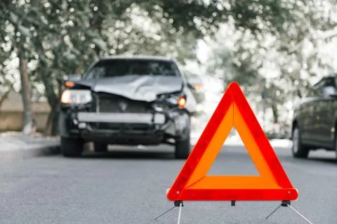 Red emergency stop triangle sign on road in car accident scene. Broken SUV car Stock Photos