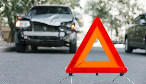 Red emergency stop triangle sign on road in car accident scene. Broken SUV car Foto stock