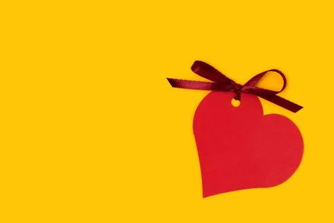 Red empty tag in a heart shape with tied ribbon bow. Stock Photos