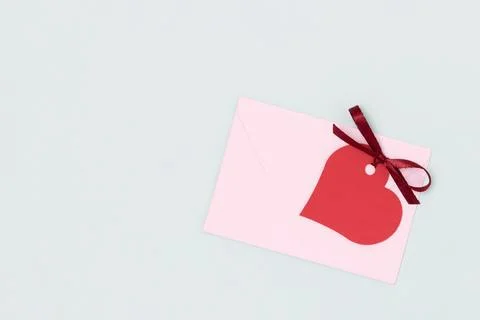 Red empty tag in a heart shape with tied ribbon bow and envelope. Stock Photos