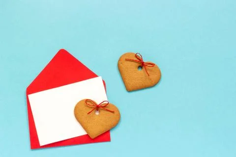 Red envelope with blank white card for text and heart shaped ginger cookies o Stock Photos