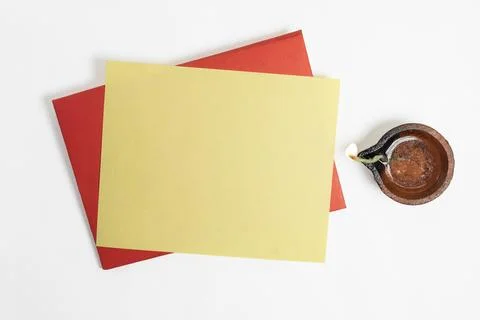 Red envelope with blank yellow paper sheets and burning clay oil lamps on w.. Stock Photos