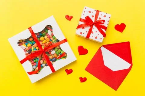 Red envelope with candy and gift box and Valentines hearts on colored backgro Stock Photos