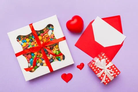 Red envelope with candy and gift box and Valentines hearts on colored backgro Stock Photos