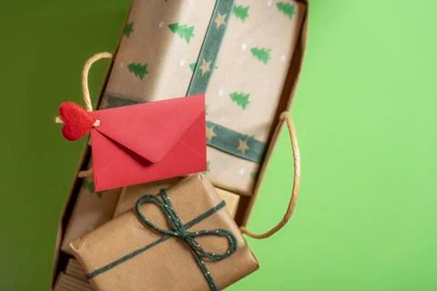 Red envelope clipped on the handle from a full of gifts bag. Top view with co Stock Photos
