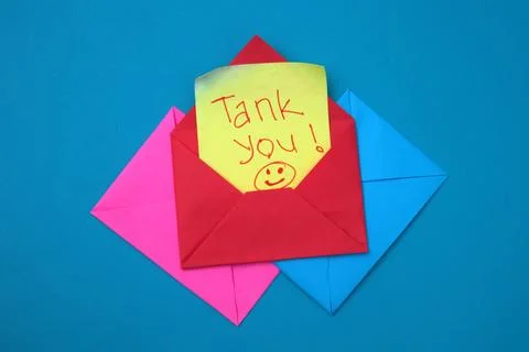 A red envelope containing a yellow sticky note with the words "thank you" w.. Stock Photos