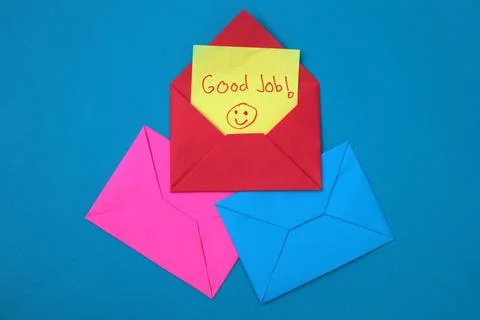 A red envelope containing a yellow sticky note that says "good job" on top .. Stock Photos