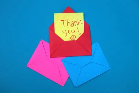 A red envelope containing a yellow sticky note with the words "thank you" w.. Stock Photos