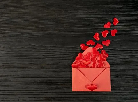 Red envelope with a heart on a black textured wooden background. Sending a .. Stock Photos