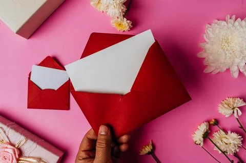 Red envelope, pink giftbox with blank card and flower on pink background Stock Photos