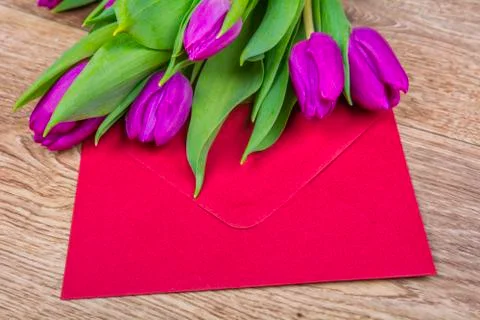 Red envelope with tulips on a table Stock Photos