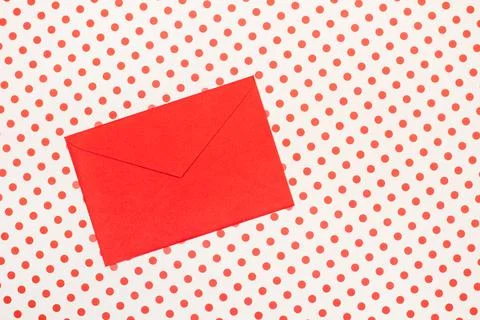 A red envelope on a white with red polka dots background with copy space Foto stock