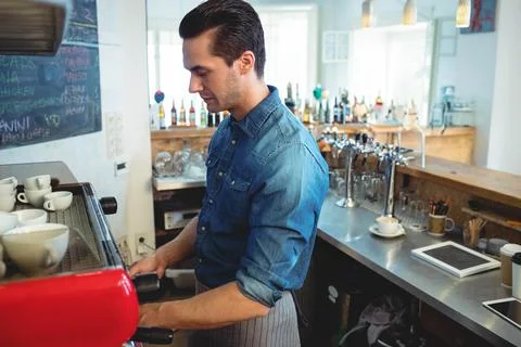 Red espresso machine brewing coffee on metal counter at cafe bar, with ceramic Stock Photos