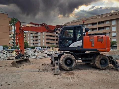 Red excavator working on construction site moving debris and earth during o.. Stockfoto's