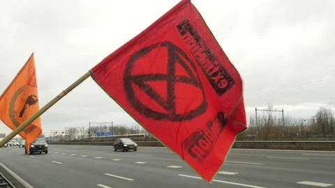 Red Extinction Rebellion flag held by activist by the road at Climate Rally. Stock Footage 266546870
