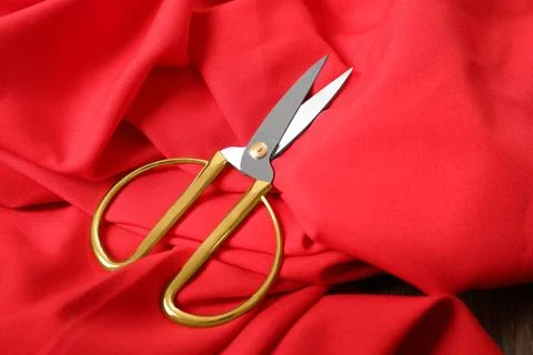 Red fabric and sharp scissors on wooden table. Space for text Stock Photos