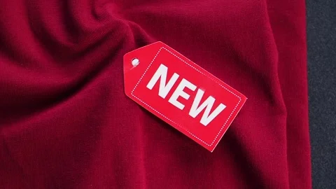 Red fabric with new tag on a black background Stock Footage 342089555