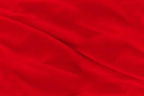 Red fabric texture background. Abstract cloth backdrop with soft waves. Stock Photos